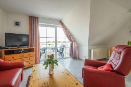 a living room with two red chairs and a television at Fehmarn 17-6 in Fehmarn