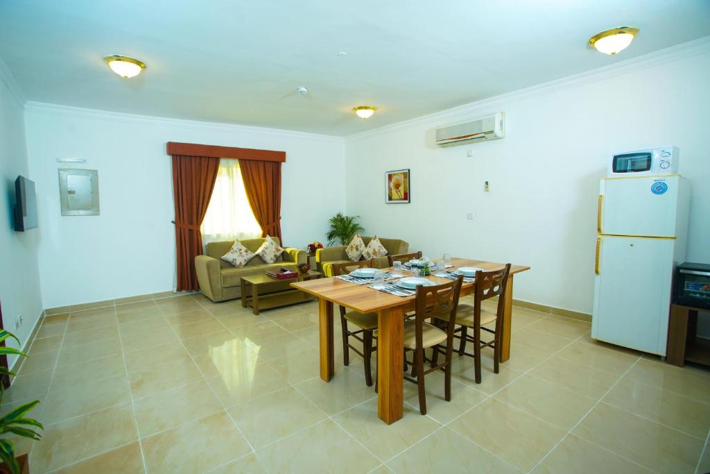 La Villa Inn Hotel Apartments في الدوحة: غرفة معيشة مع طاولة وأريكة