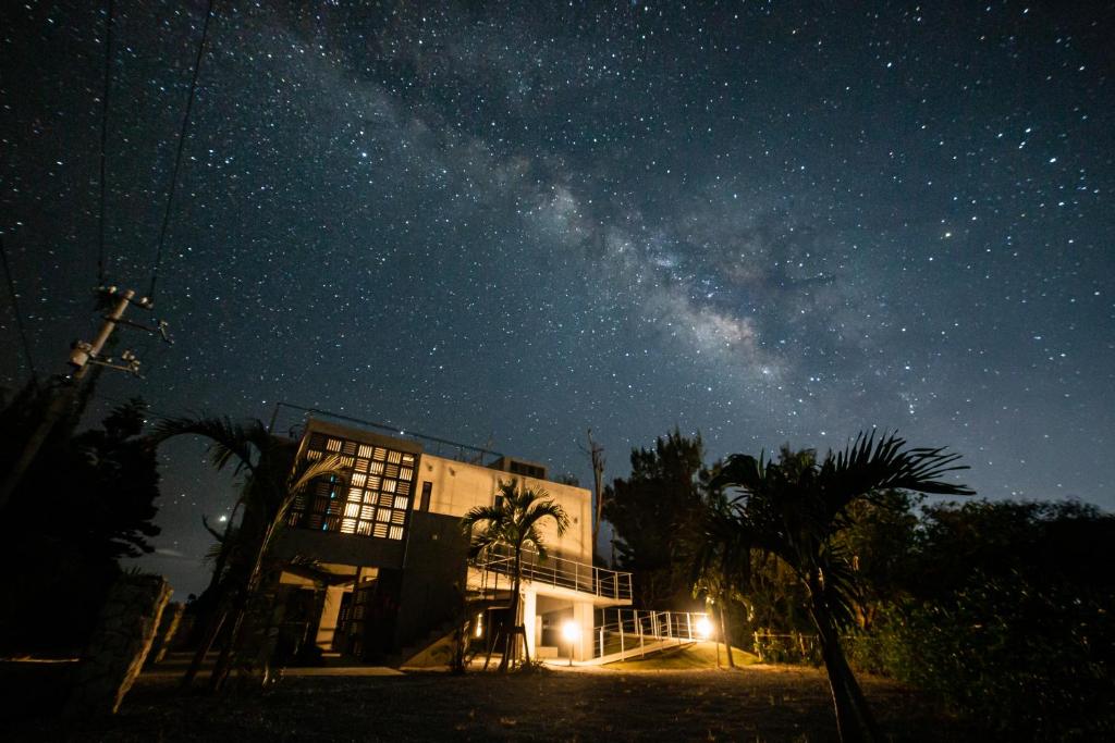 un edificio bajo un cielo nocturno con la Vía Láctea en Kouri beach side villa YUMANDI, en Nakijin