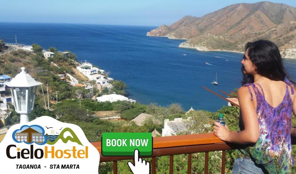 a woman standing on a balcony looking at the ocean at Cielo Hostel in Taganga