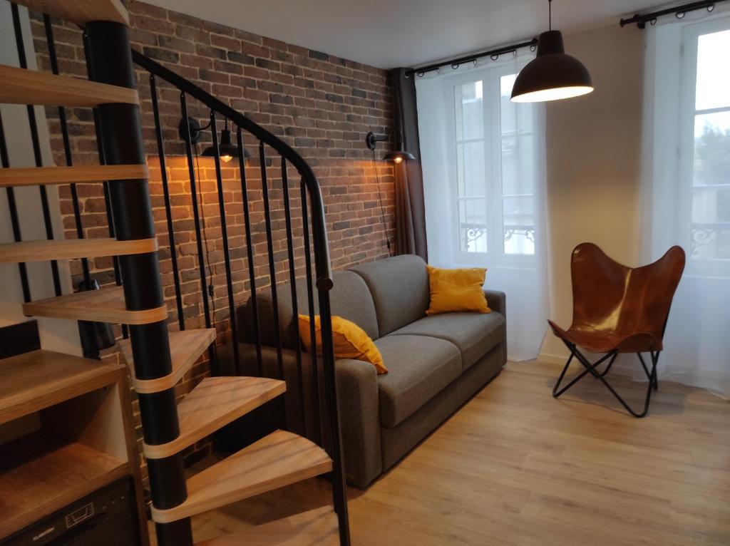 a living room with a couch and a brick wall at Gites les Pourquoi Pas - Résidence de Tourisme DSV Bayeux in Bayeux