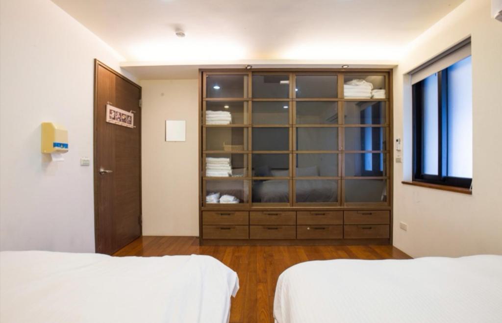 a bedroom with two beds and a glass cabinet at 建築師湧泉泡湯會館 in Dongshan