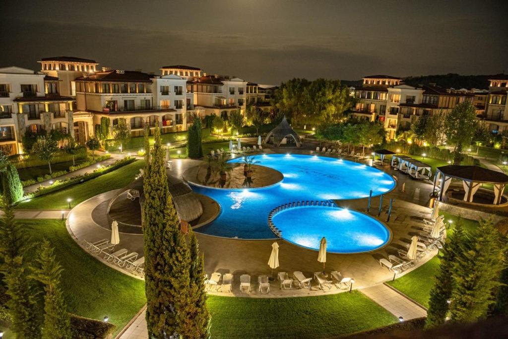 a large swimming pool in a resort at night at Green Life Beach Resort Apartment in Sozopol