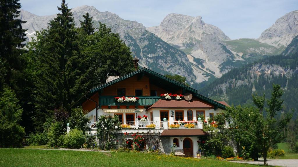 a house with flowers on the balcony in front of mountains at Haus Waltraut in Ramsau am Dachstein