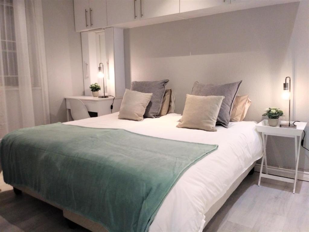 um quarto com uma cama grande com lençóis brancos e verdes em Private Loadshedding free Flatlet, Fibre WiFi, Netflix, Security Deposit applies em Krugersdorp