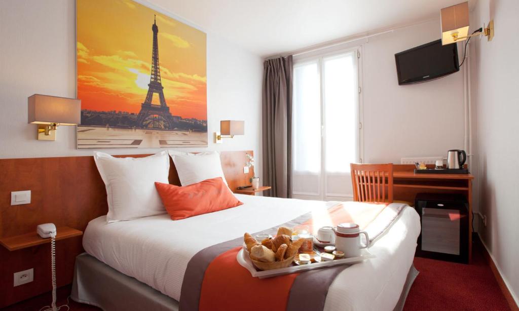 Una habitación de hotel con una cama con una bandeja de comida. en Alyss Saphir Cambronne Eiffel en París