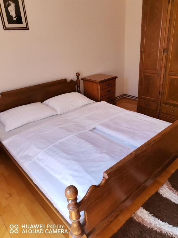 1 cama con marco de madera y sábanas blancas en Apartmens Kenedy lux en Kiseljak