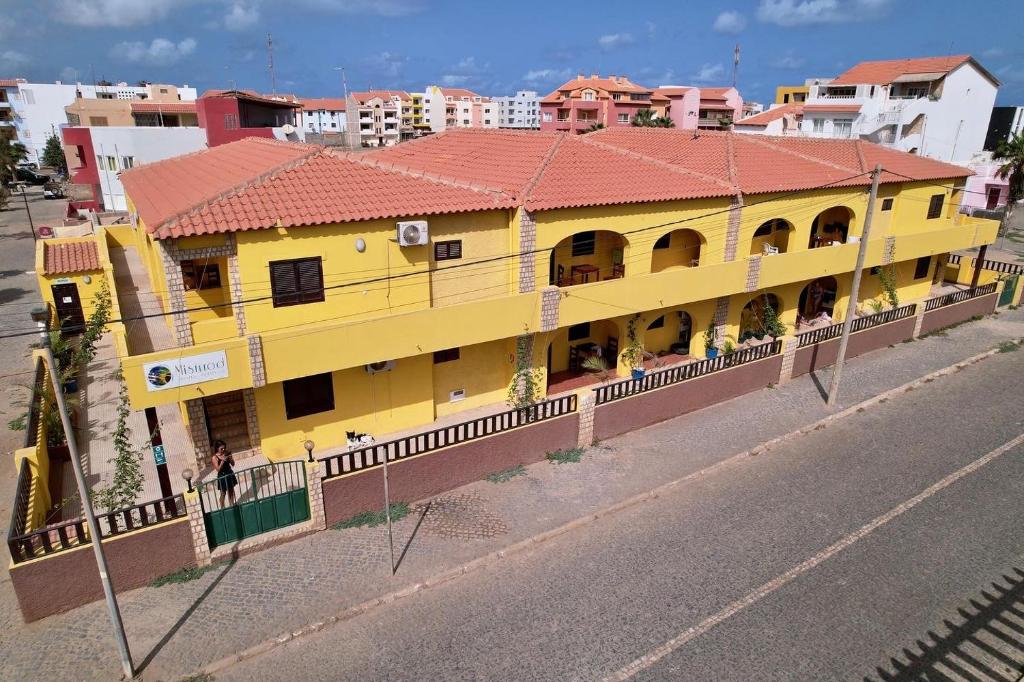 a yellow building with a red roof on the side of a street at Misturod - Holiday Apartments in Santa Maria