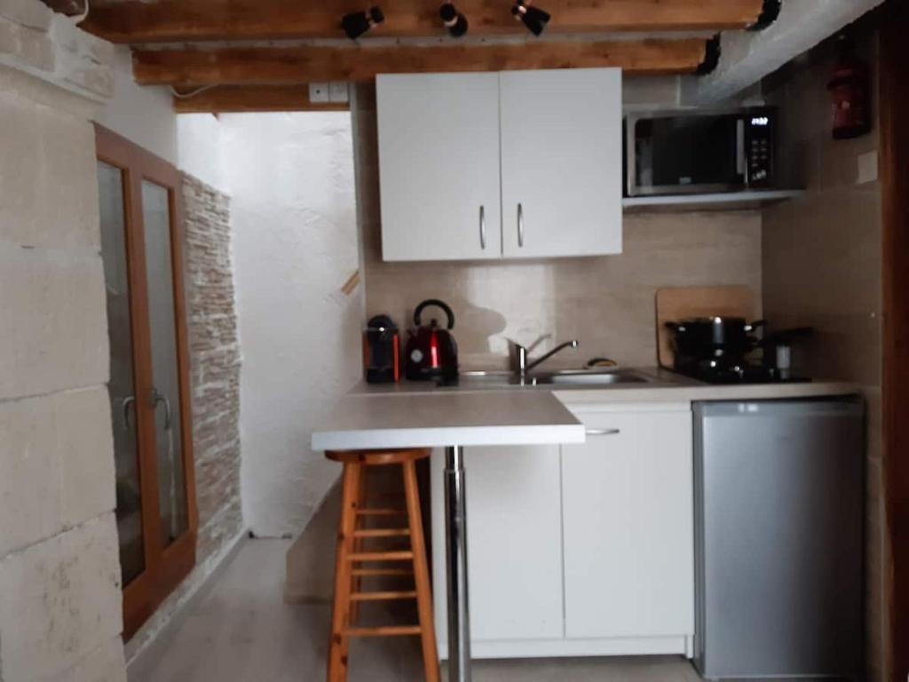 a kitchen with white cabinets and a sink and a stool at Garden Annexe 2 in Villeneuve-Loubet