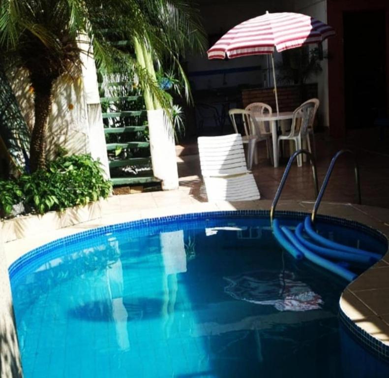 - une piscine avec un parasol, une table et des chaises dans l'établissement Pousada Charme Charmant, à Praia Grande