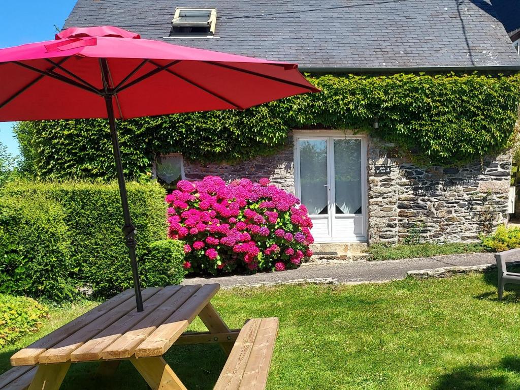 a wooden bench with a red umbrella in front of a house at Ty Coz in Saint-Ségal