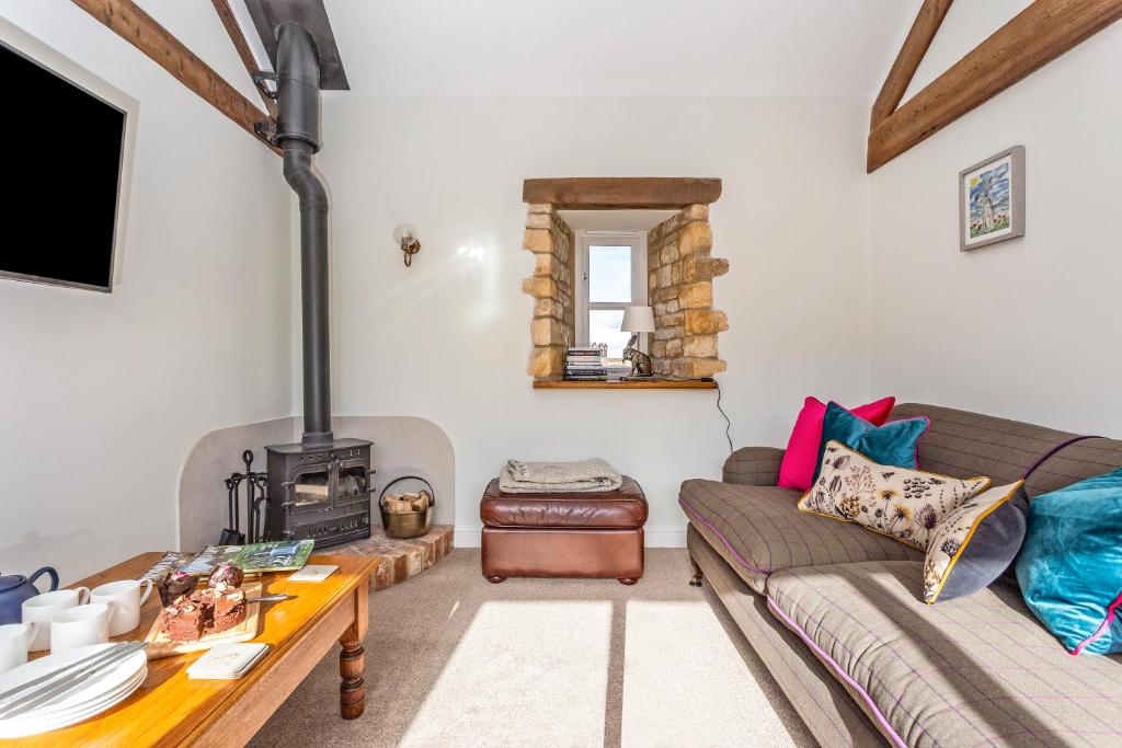 uma sala de estar com um sofá e um fogão a lenha em 1 Homepiece em Chipping Campden