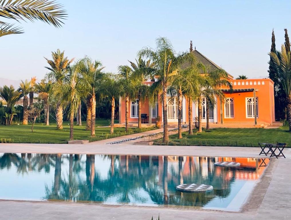 an orange house with palm trees and a swimming pool at The Levantine in Marrakesh