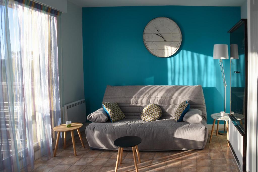 un salon avec un canapé et une horloge au mur dans l'établissement Joli appartement F3 - 50m de la mer, à Cabourg