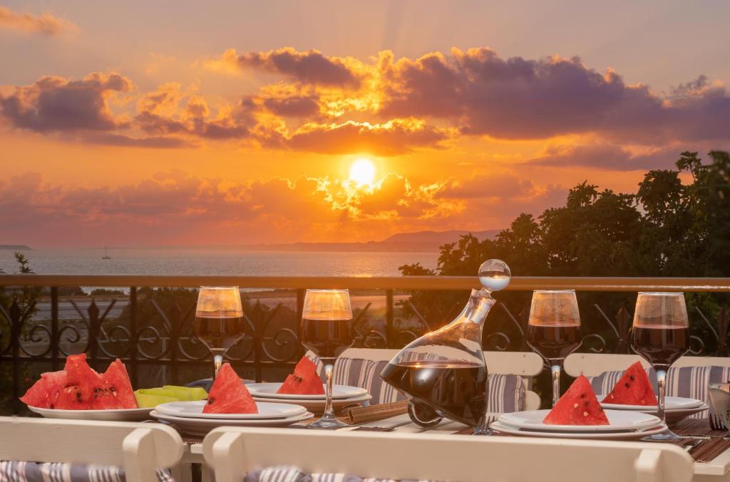 a table with watermelon plates and wine glasses at sunset at Dimitra Apartments & Studios in Minia