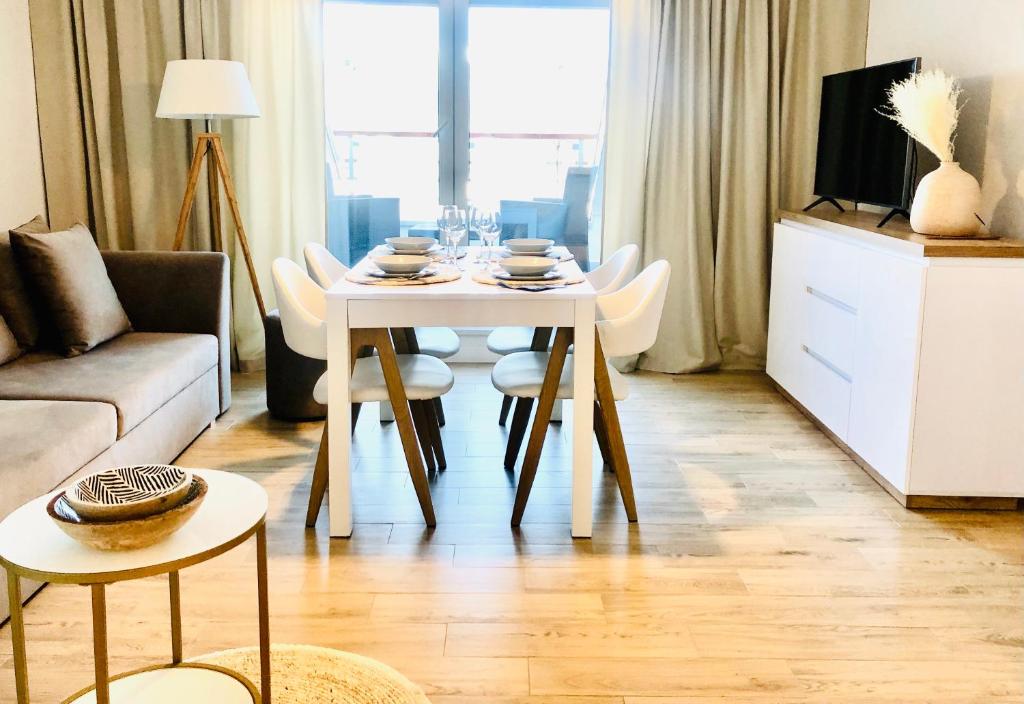 - un salon avec une table et des chaises blanches dans l'établissement Syrenka apartament, à Darłowo