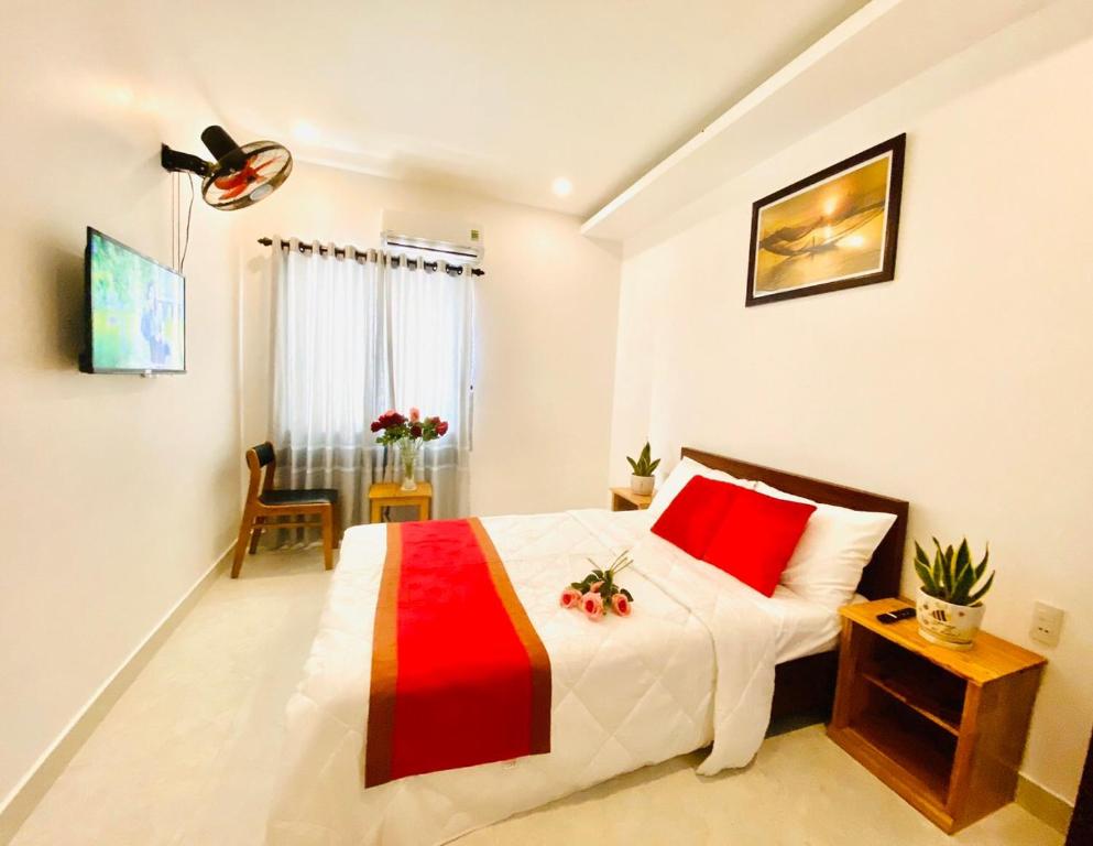 een slaapkamer met een bed met een rode en witte deken bij Toro Homestay in Hội An