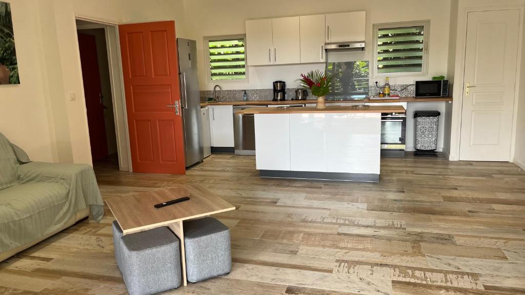 a kitchen and living room with a table and a couch at Les Gîtes de la Lézarde in Petit-Bourg