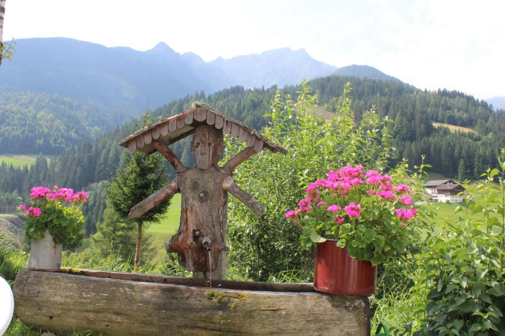 a statue of a cross with flowers in a garden at Gasthof Luggau in Maria Luggau