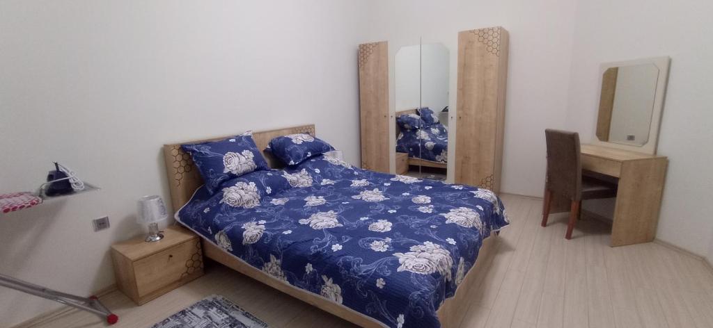 Schlafzimmer mit einem Bett mit blauer Decke und einem Spiegel in der Unterkunft Large and central apartment in the heart of Baku, close to Icheri Sheher Metro station and the Fountain Square in Baku