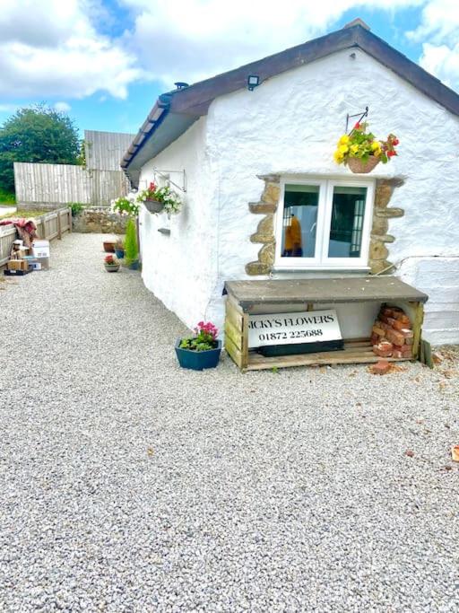 a small white building with a window and flowers at Romantic log-burner Cornish Cottage private garden dogs welcome in Truro