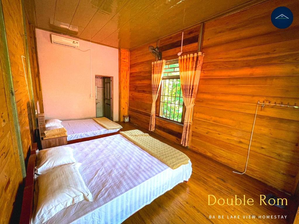 1 dormitorio con 2 camas y ventana en Ba Be Lake View Homestay, en An Ma