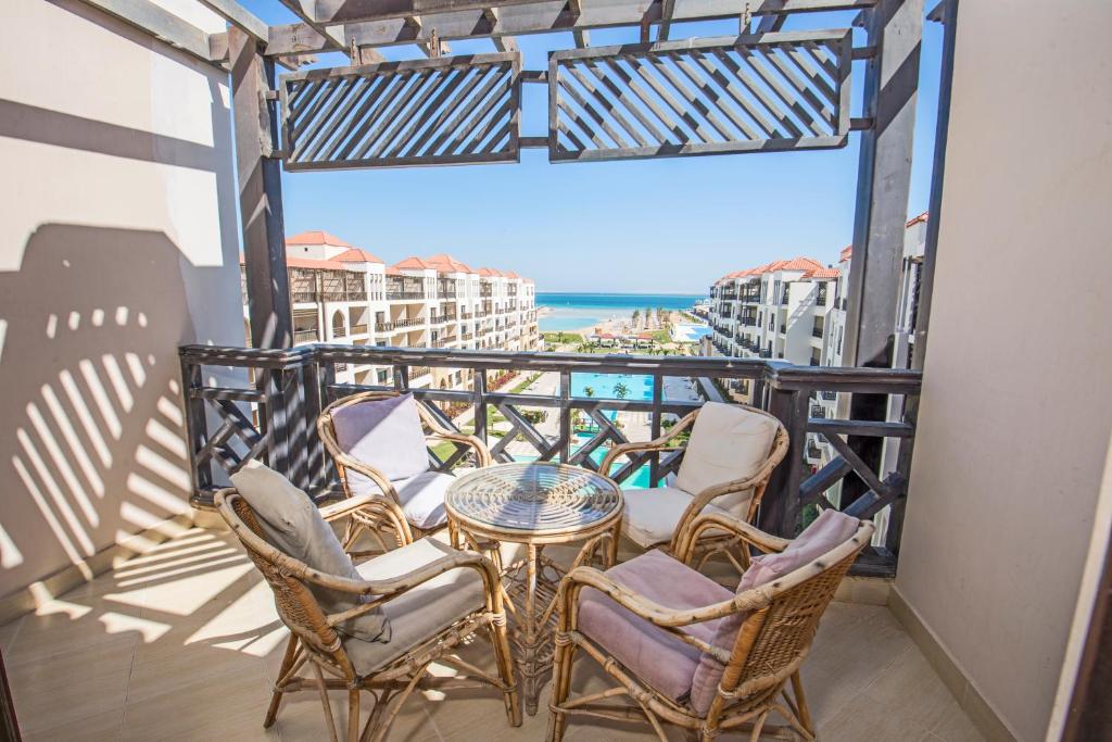 een balkon met stoelen en een tafel en uitzicht op de oceaan bij Premium sea view 2 bedrooms 2 bathrooms apartment located within Gravity Hotel & Aquapark Hurghada in Hurghada