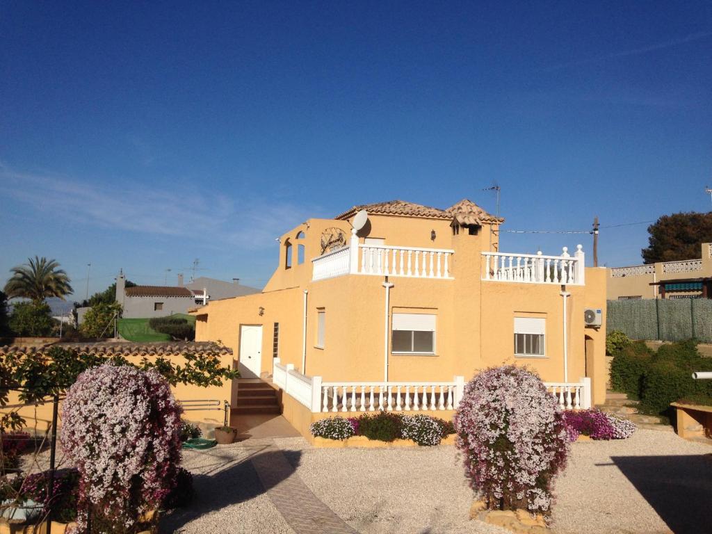 ein großes gelbes Haus mit einem weißen Balkon in der Unterkunft Pete's Place in La Marina