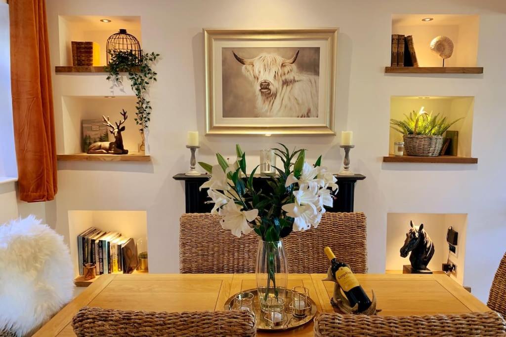 Renovated Miner’s Cottage - family & dog friendly في Abertillery: طاولة غرفة الطعام مع إناء من الزهور عليها