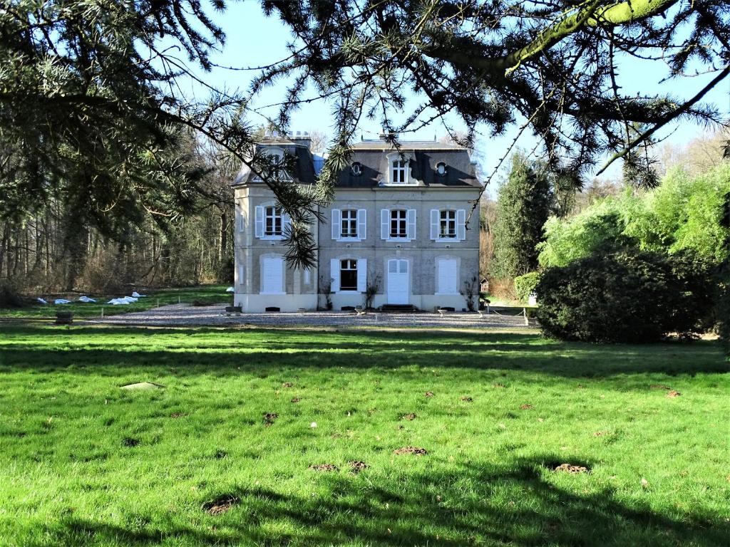 uma grande casa branca sentada no topo de um exuberante campo verde em Gîte Chateau baie de somme 10 a 12 personnes em Mons-Boubert
