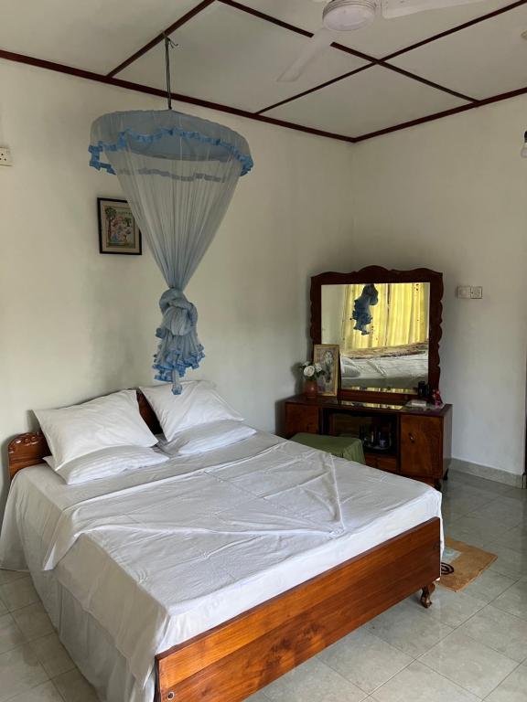 een slaapkamer met een bed en een dressoir met een spiegel bij Summer Ridge - Homestay in Ratnapura