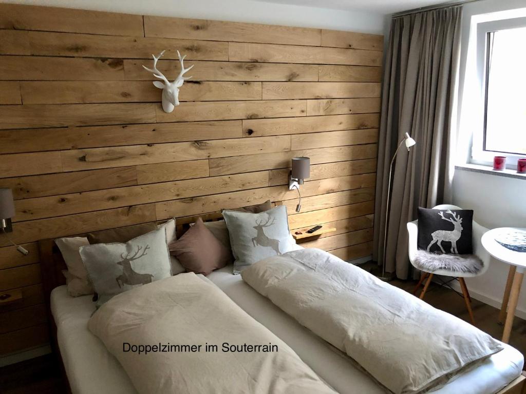 a bedroom with a wooden accent wall and a bed at Hirschzimmer & Strandzimmer in Utting am Ammersee