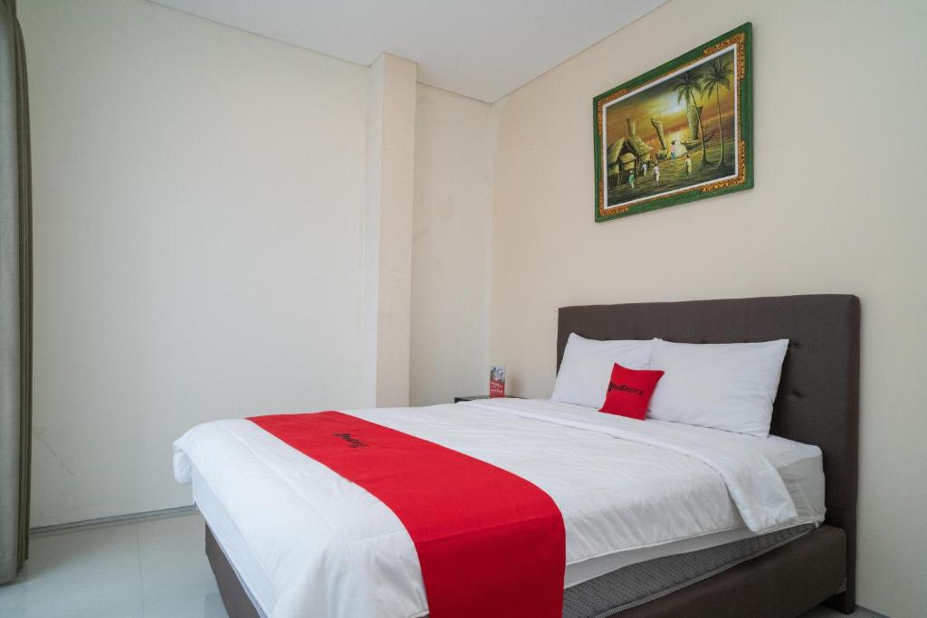 a bedroom with a bed with a red and white blanket at RedDoorz near ITDC Nusa Dua in Nusa Dua