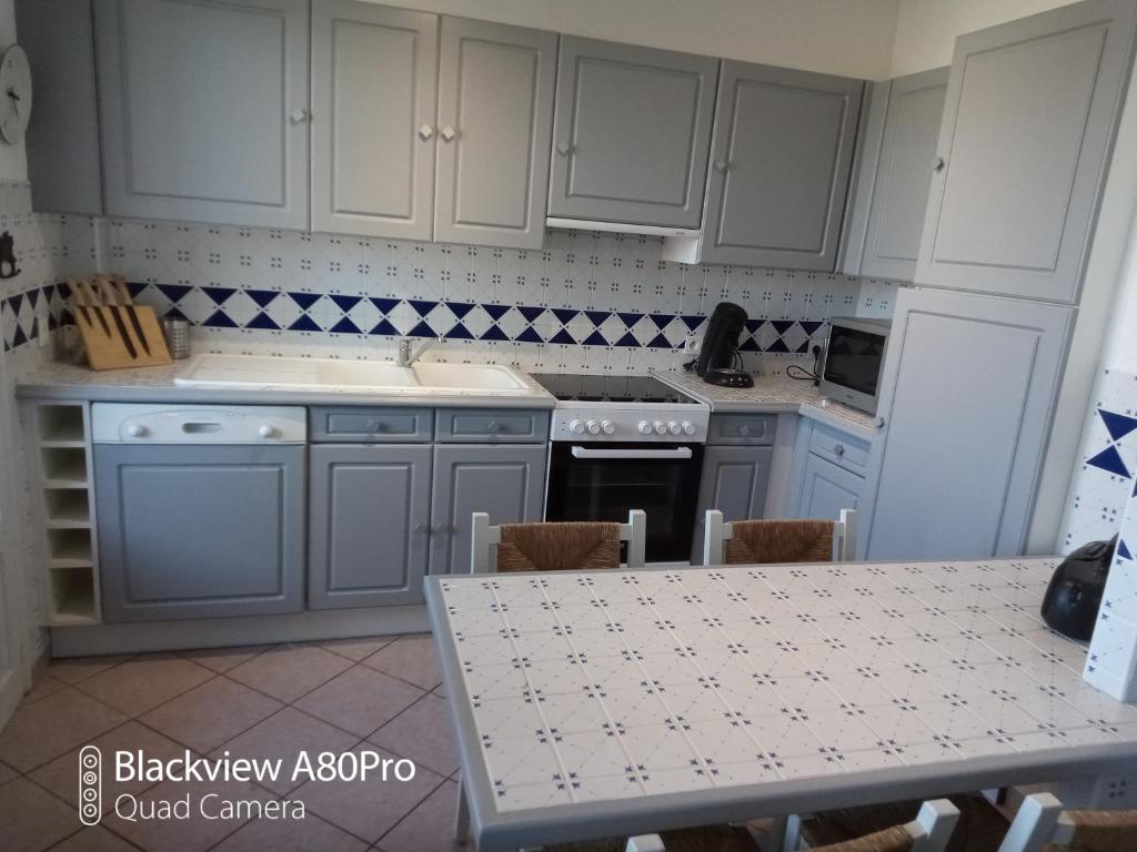 een keuken met witte kasten en een tafel en een tafel en een tafel bij appartement du pecheur in Valras-Plage