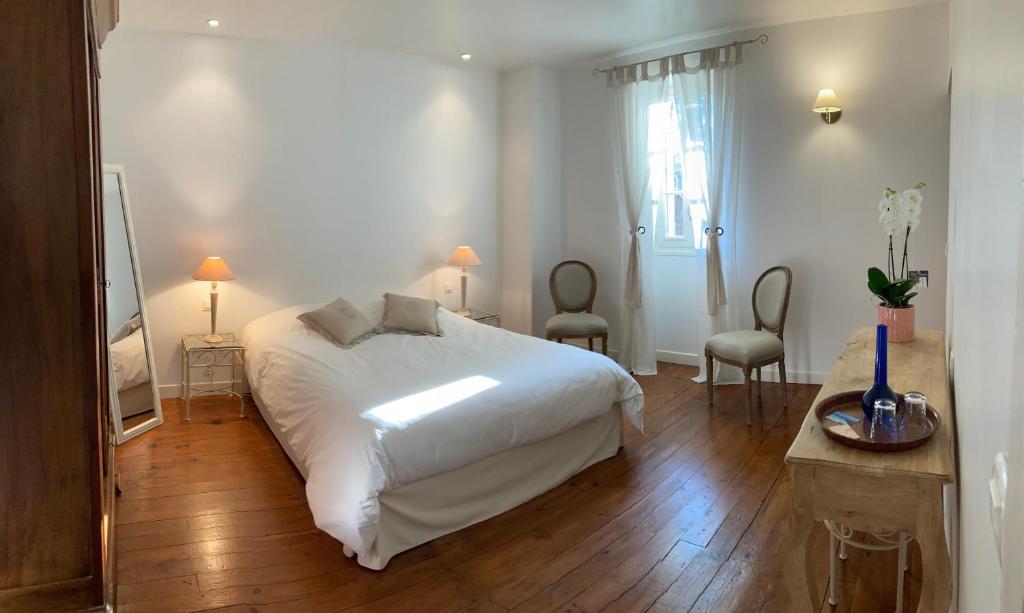 une chambre avec un lit blanc et deux chaises dans l'établissement Le Clos de Longas - Gite et Chambre d'hôtes, à Sainte-Foy-de-Longas
