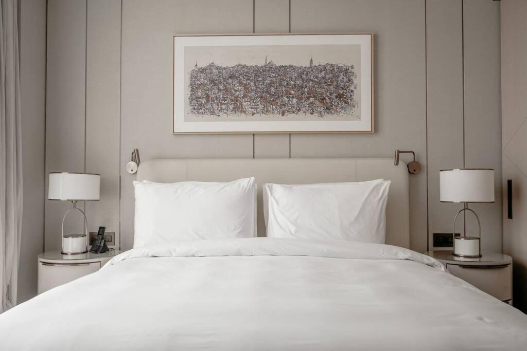 1 dormitorio con 1 cama blanca grande y 2 lámparas en Serviced Luxurious 3+1 in Address Emaar Square en Estambul