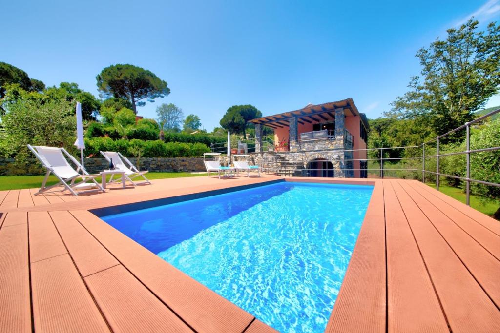 einen Pool mit zwei Stühlen und ein Haus in der Unterkunft I Giardini di Camogli - VILLA RUMANIN, garden&pool in Camogli