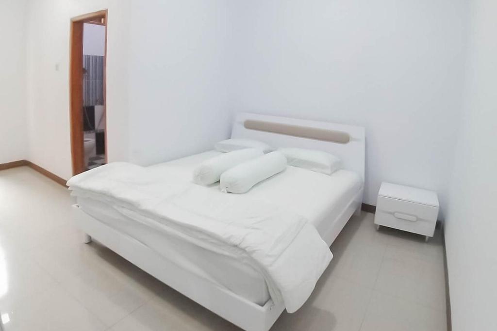ein Schlafzimmer mit einem weißen Bett mit weißer Bettwäsche und Kissen in der Unterkunft Angel Guest House Lembang RedPartner in Lembang