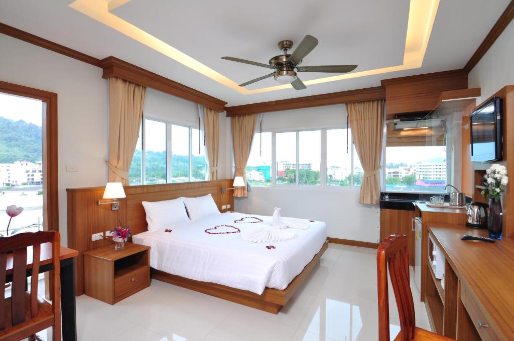 a bedroom with a bed and a kitchen with windows at Green Harbor Hotel & Service Apartment in Patong Beach