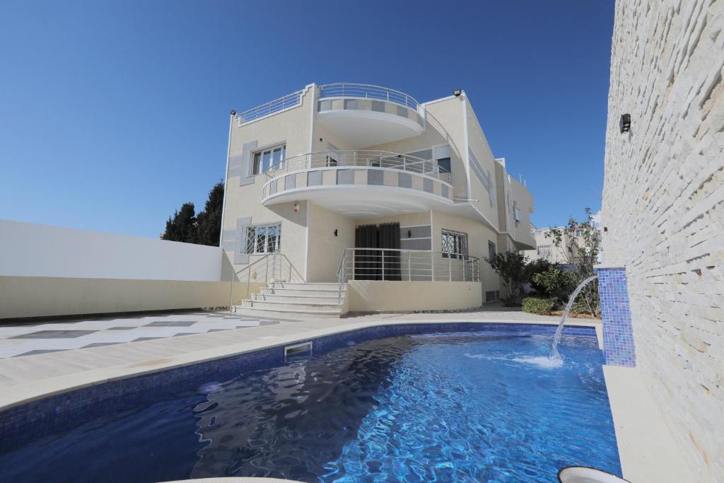 une grande maison avec une piscine en face de celle-ci dans l'établissement Magnifique Villa Avec Piscine, Pour Vos Vacances !, à Monastir