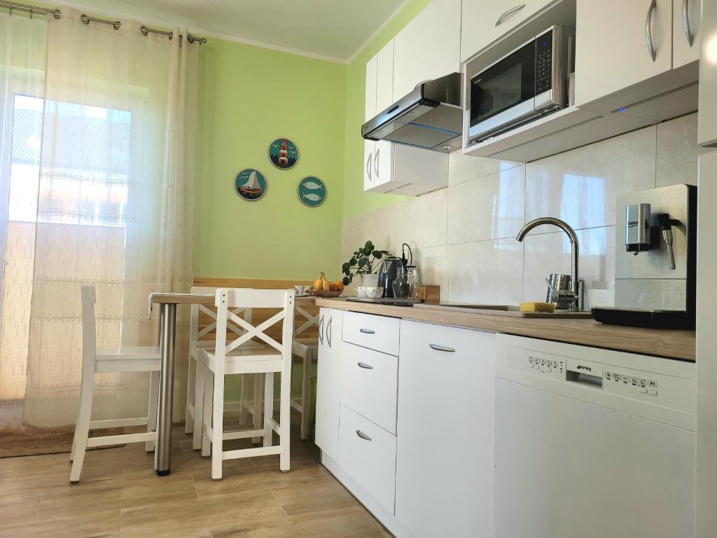 a kitchen with white cabinets and a table and a microwave at Apartament Laurowy in Darłowo
