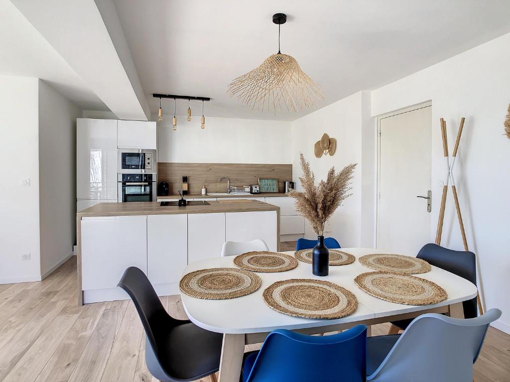 een keuken en eetkamer met een witte tafel en stoelen bij ** Superbe appartement sur le canal du midi ** in Laredorte