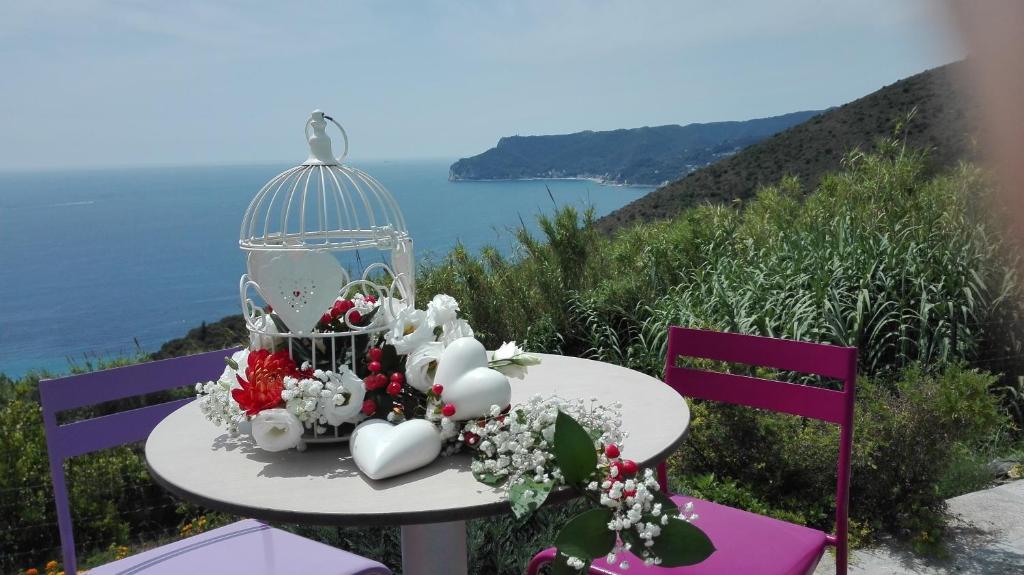 a table with flowers and a bird cage at Oroverde in Bergeggi