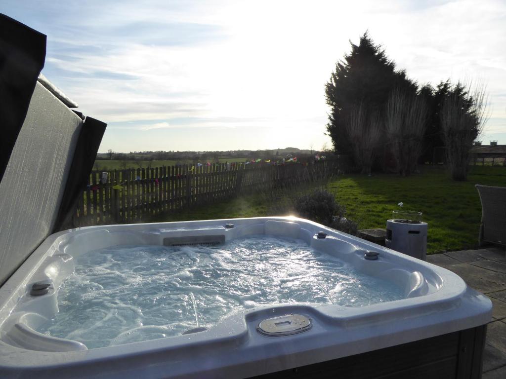 a jacuzzi tub sitting in a yard with the sun shining at South View Country House Sleeps 12 - Hot Tub - Views in Henley in Arden