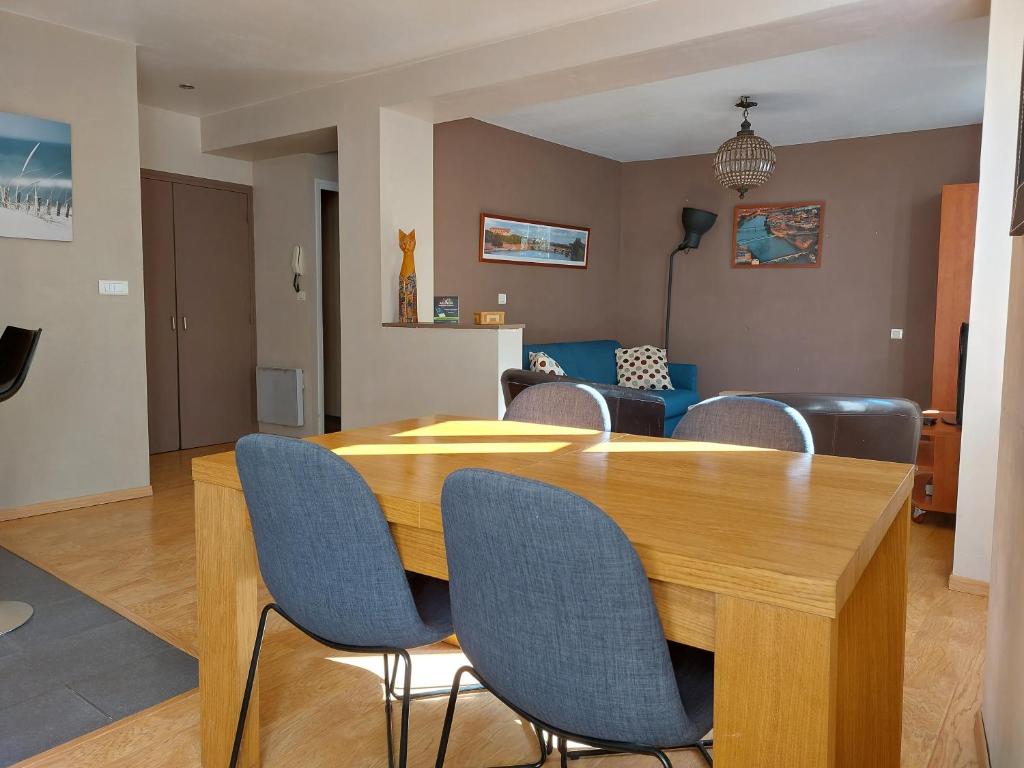 Le Bullière 60m2 plein centre! في روديه: غرفة معيشة مع طاولة وكراسي خشبية