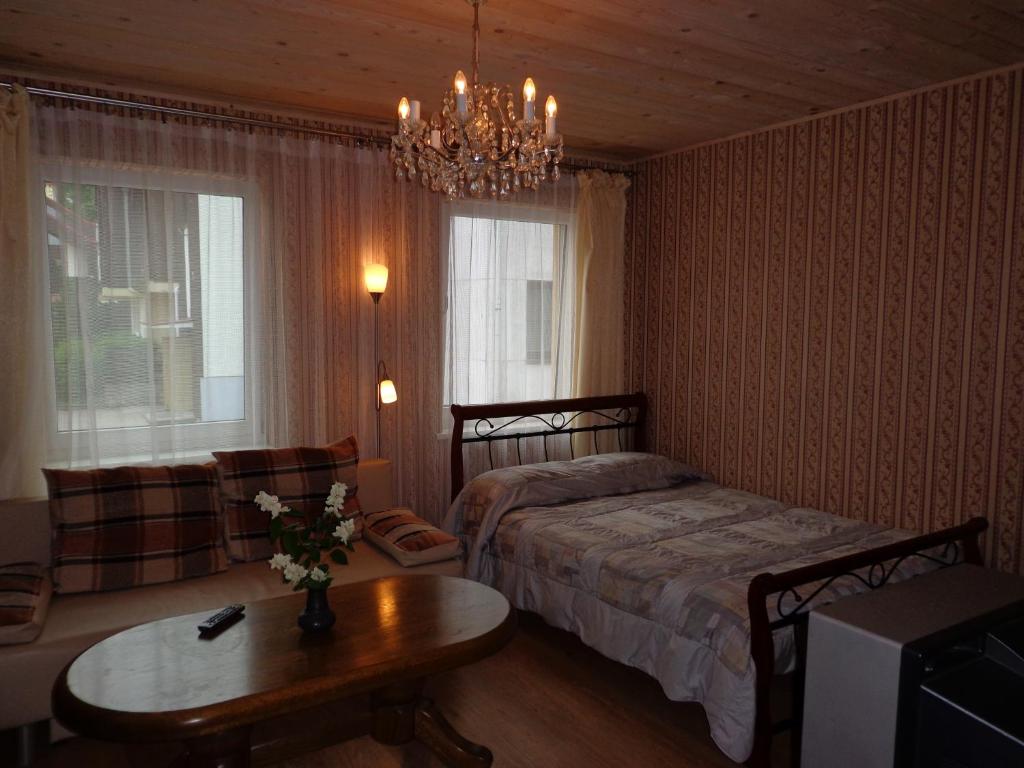 una camera con letto, tavolo e lampadario a braccio di Birutės Alėja 20 a Palanga