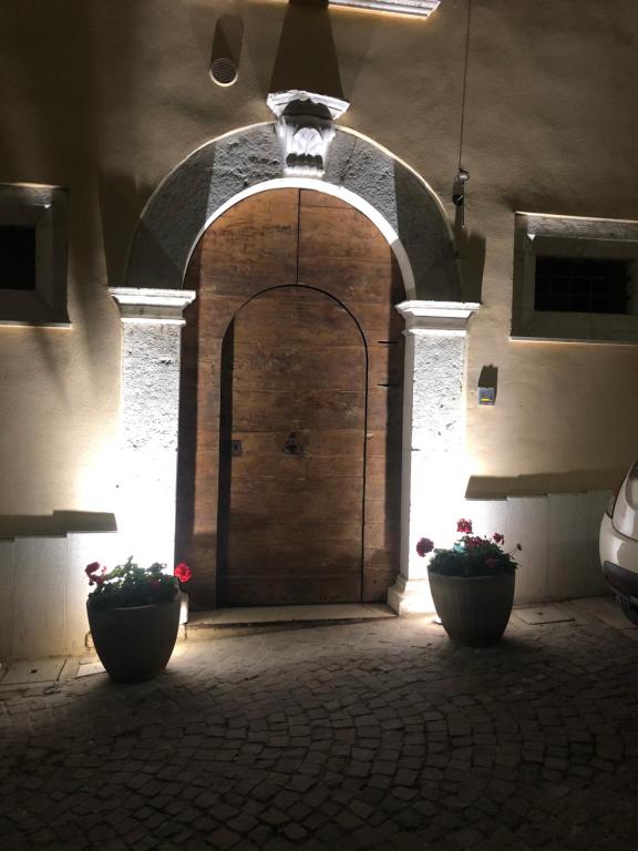 a large wooden door in a building with two pots at Palazzo del Principe in Castel di Sangro