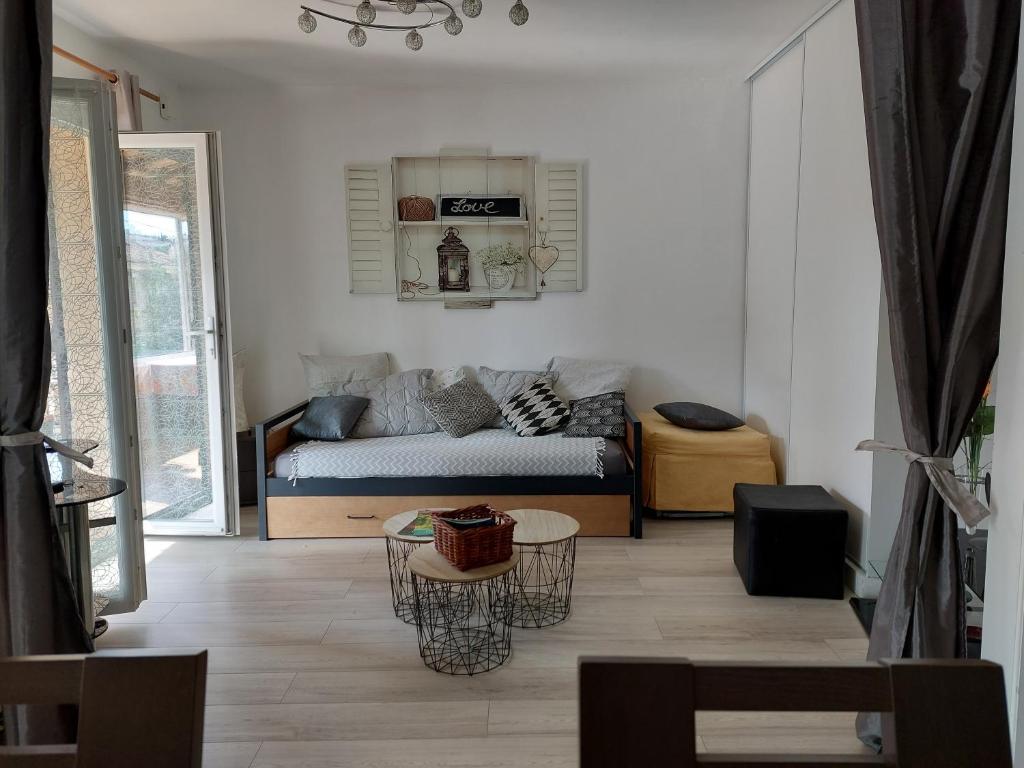 een woonkamer met een bank en een tafel bij Home Tranquille Dans la Cité du Mimosa - 2 étoiles - Axelle Loc'Appart in Mandelieu-la-Napoule