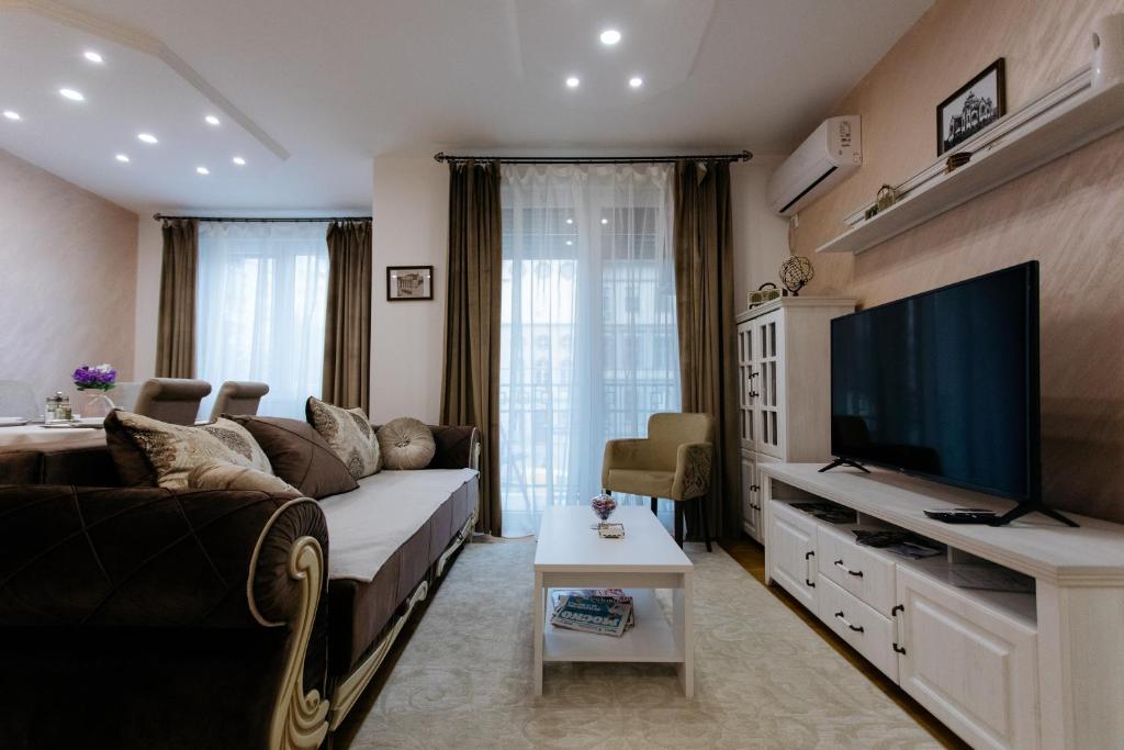 ein Wohnzimmer mit einem Sofa und einem Flachbild-TV in der Unterkunft Apartman Kristina 4* in Subotica