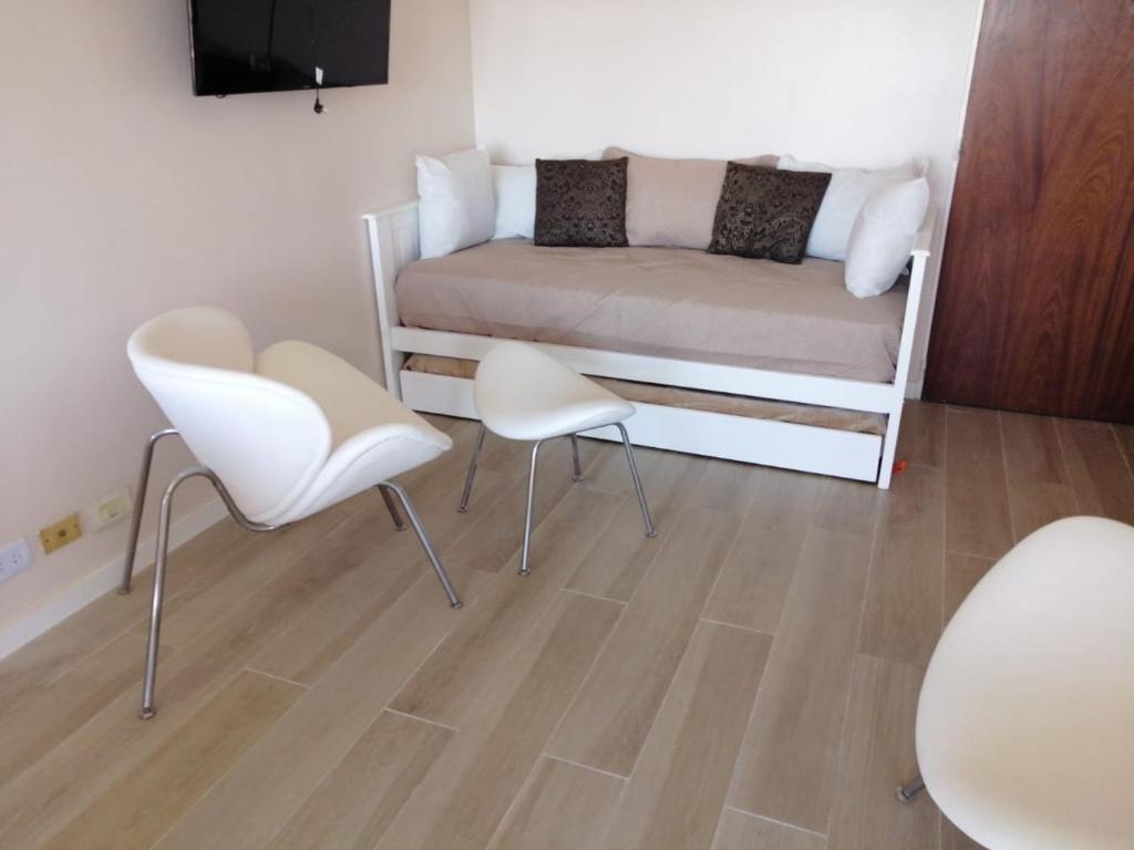ein kleines Zimmer mit einem Bett und zwei weißen Stühlen in der Unterkunft Petit Apartment en Avenida Belgrano in Buenos Aires